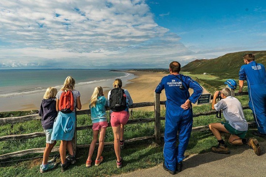 A group of people standing by a railing overlooking a beach. 5