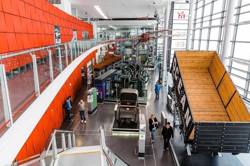 A large indoor space with a red wall, a wooden structure, and various machinery. 3
