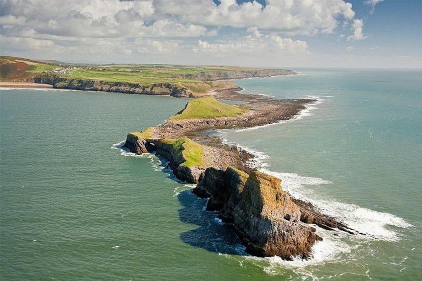 A coastal landscape with cliffs, a beach, and a distant shoreline. 1