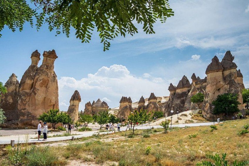 A landscape with unique rock formations, a paved path, and a few people walking. 1