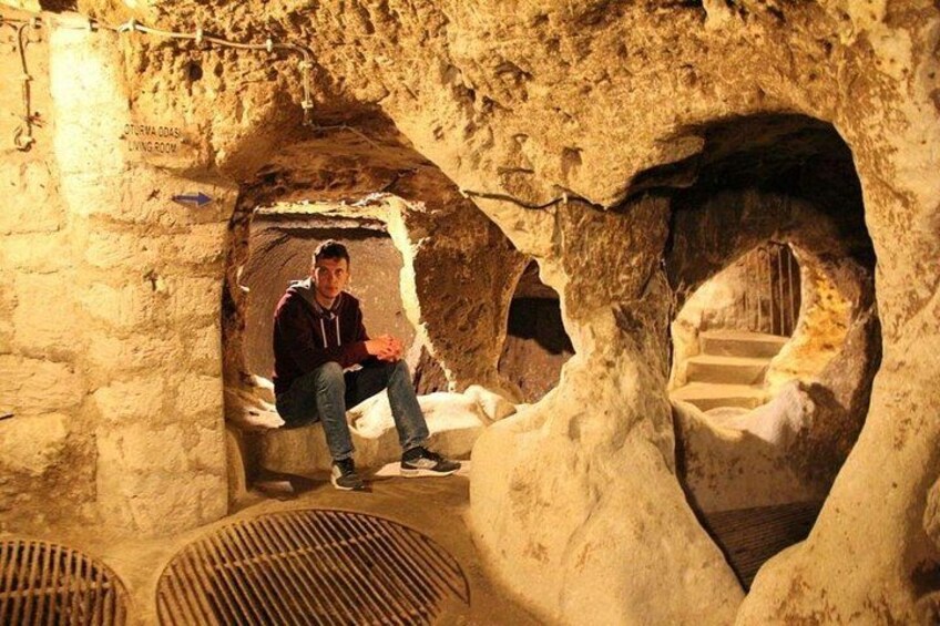 A person sitting in a cave-like structure with stone walls and a staircase leading down. 2