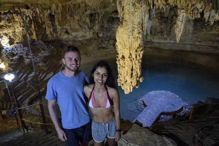 A cave with stalactites and stalagmites, a wooden platform, and a person standing on the platform. 5