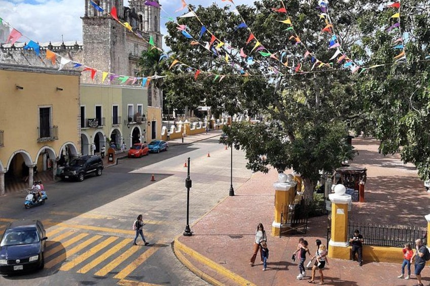 A street with pedestrians, cars, and colorful flags. 2