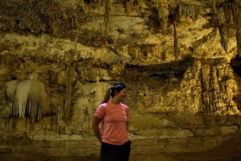 A person standing in a cave with stalactites and stalagmites. 5