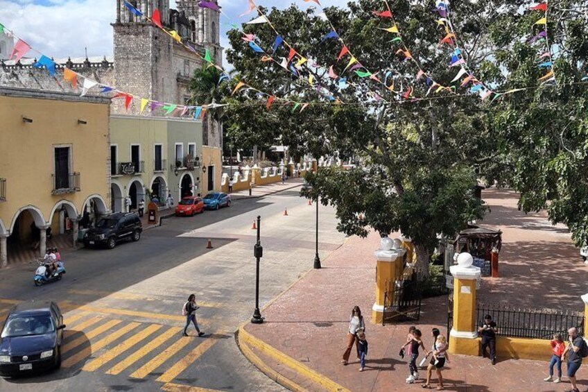 A street with buildings, a tree, and people walking. 3