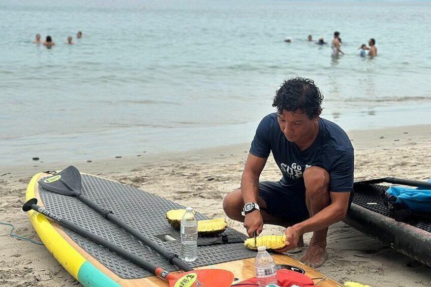 A person preparing a paddleboard on a sandy beach with the ocean in the background. 3
