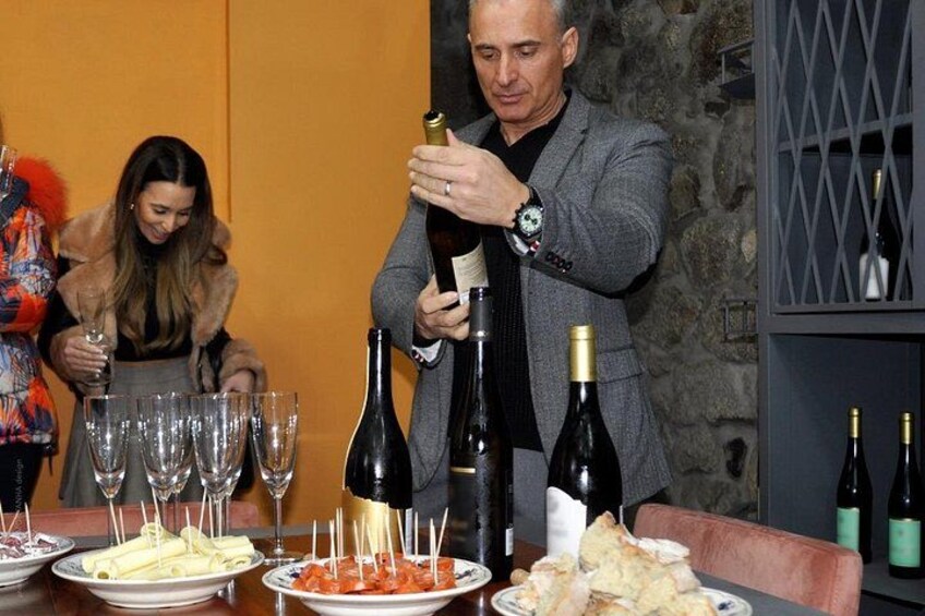 Un uomo versa del vino in bicchieri a un tavolo apparecchiato con piatti di cibo. 1