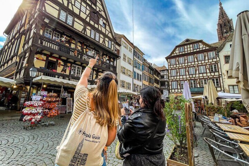 A cobblestone street with historic buildings and a market stall. 1