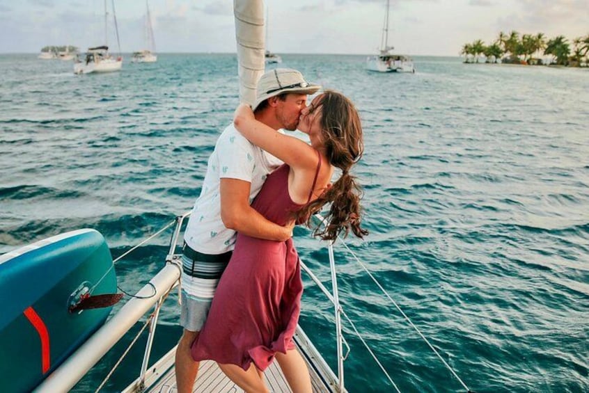 A couple embracing on a sailboat with the ocean and other boats in the background. 5