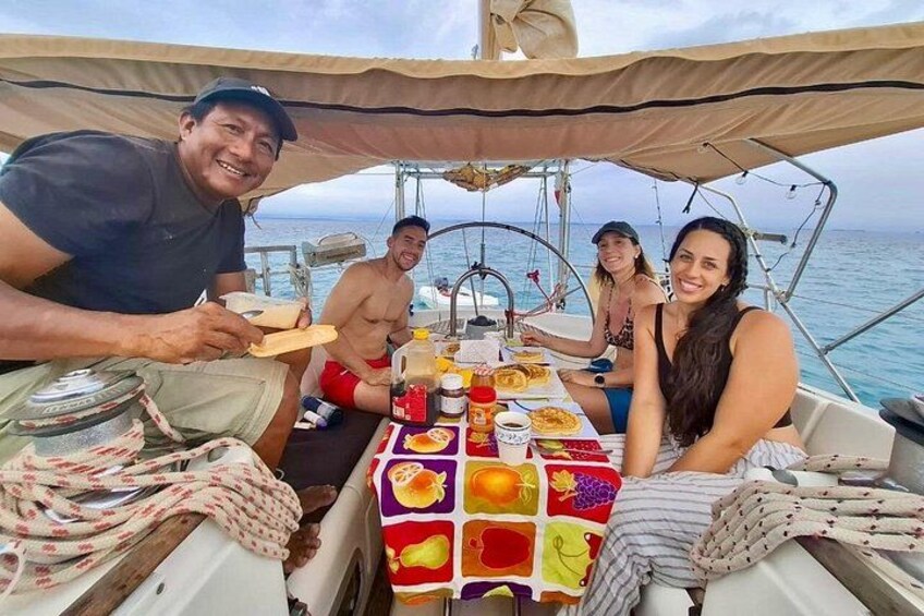 A group of people on a sailboat with a table set for a meal. 4