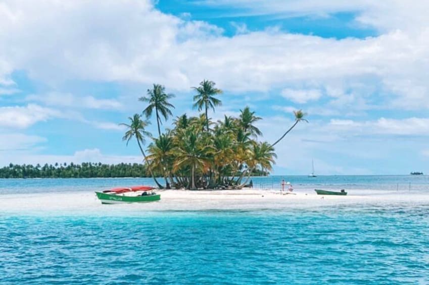 A tropical island with a white sand beach, palm trees, and two boats. 3