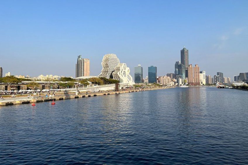 Un paisaje urbano frente al agua con arquitectura moderna, que incluye un edificio esférico distintivo y un rascacielos alto. 2