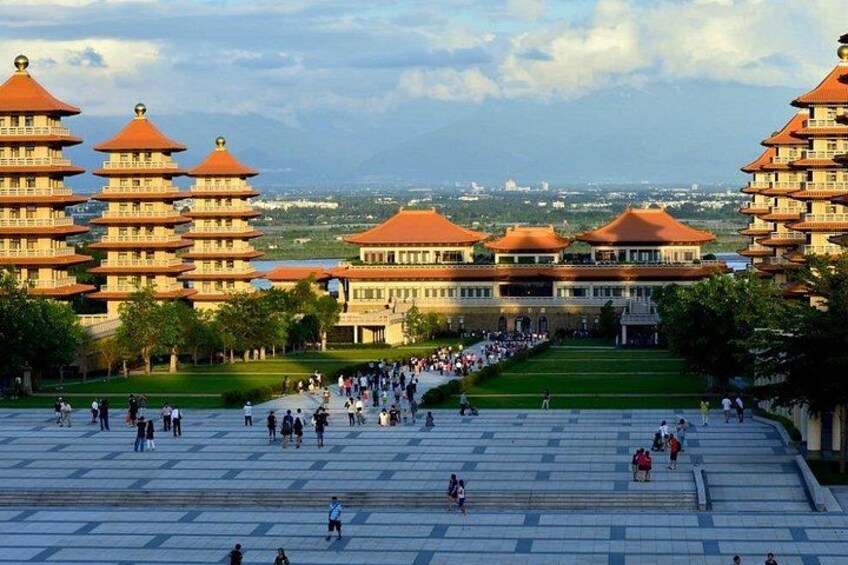 Una gran plaza abierta con edificios tradicionales de varios niveles, una multitud numerosa y una vista distante del horizonte urbano. 4