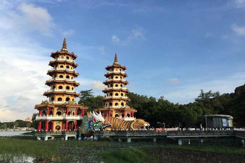 Un templo de estilo pagoda con múltiples niveles, una escultura de dragón y una masa de agua al frente. 5