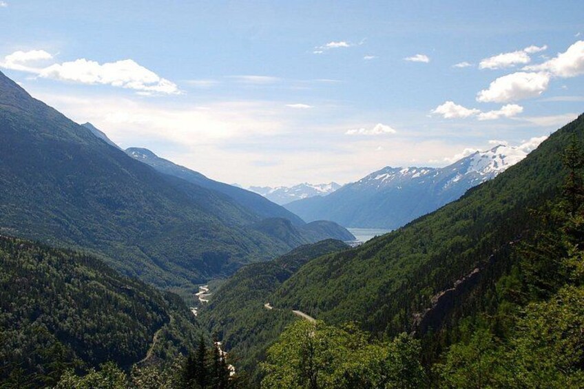 A mountainous landscape with a valley, a winding road, and a lake. 4