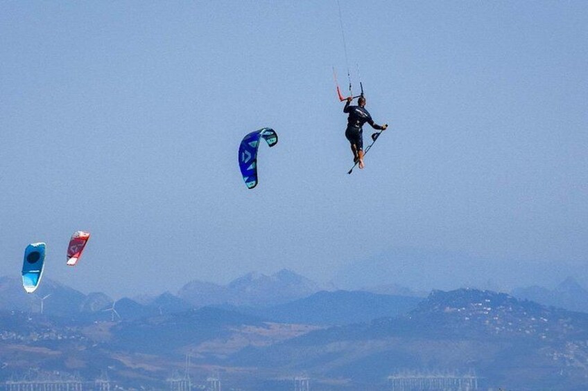 A person kiteboarding with multiple kites in the sky. 5