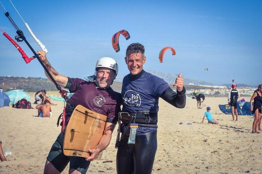 Two people on a beach with kites and a parachute. 4