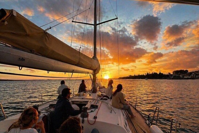 A sailboat with people on deck during sunset. 1