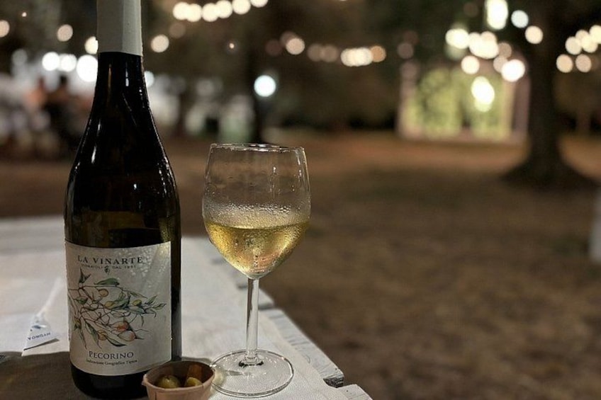 En flaske La Vinarte Pecorino vin og et glas hvidvin på et bord. 5