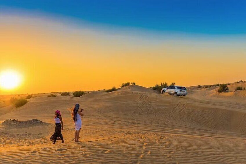 A desert landscape with sand dunes and a white vehicle in the distance. 4