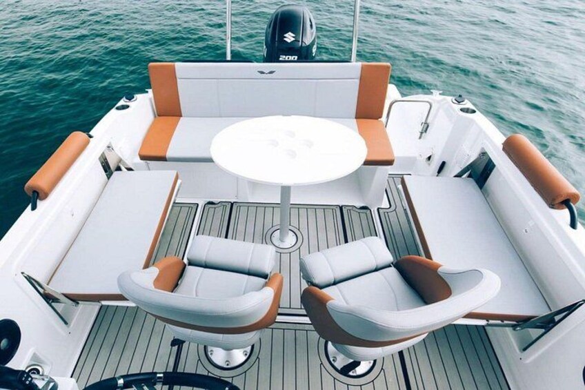 A boat deck with a table and two chairs, a steering wheel, and a wakeboard. 5