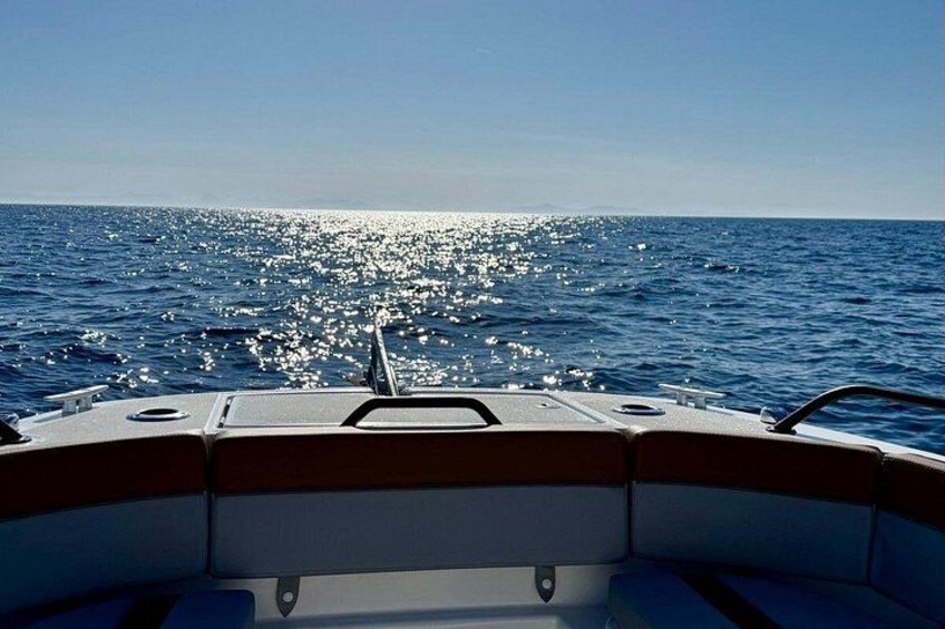 A boat on the water with a clear view of the horizon and the sun reflecting off the surface. 4