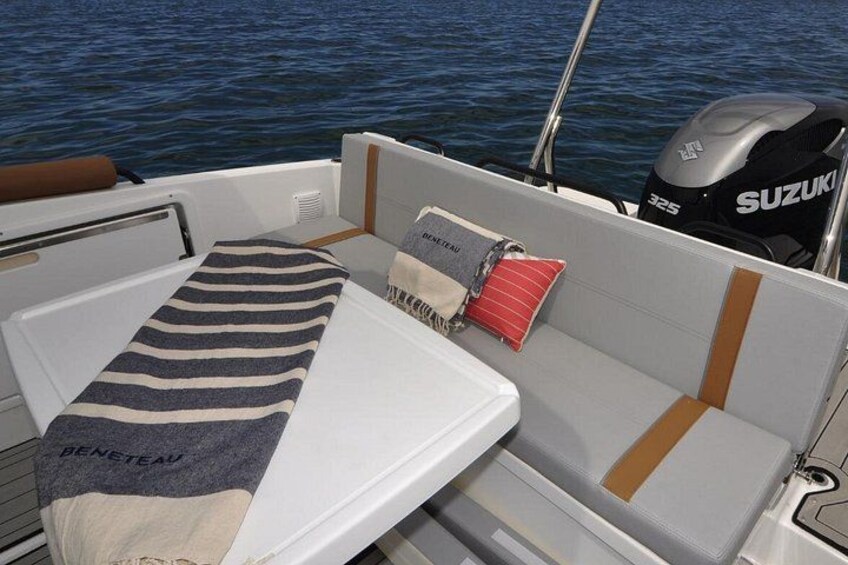 A boat interior with a Suzuki outboard motor, a striped towel, and a cushion with text. 2