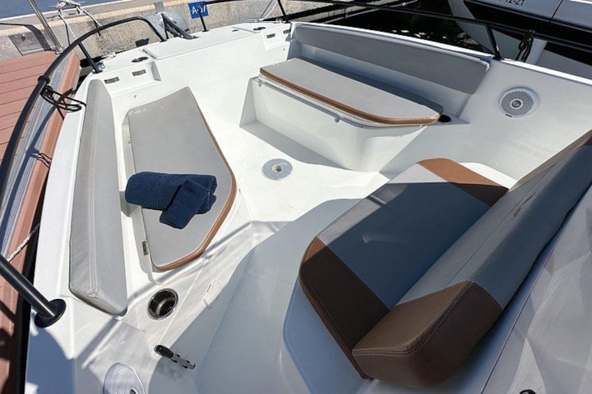 A boat's interior with seating areas, a steering wheel, and a blue towel. 3
