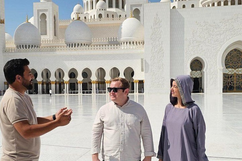 Un groupe de personnes se tient devant un grand bâtiment blanc orné de coupoles et d’arches. 2