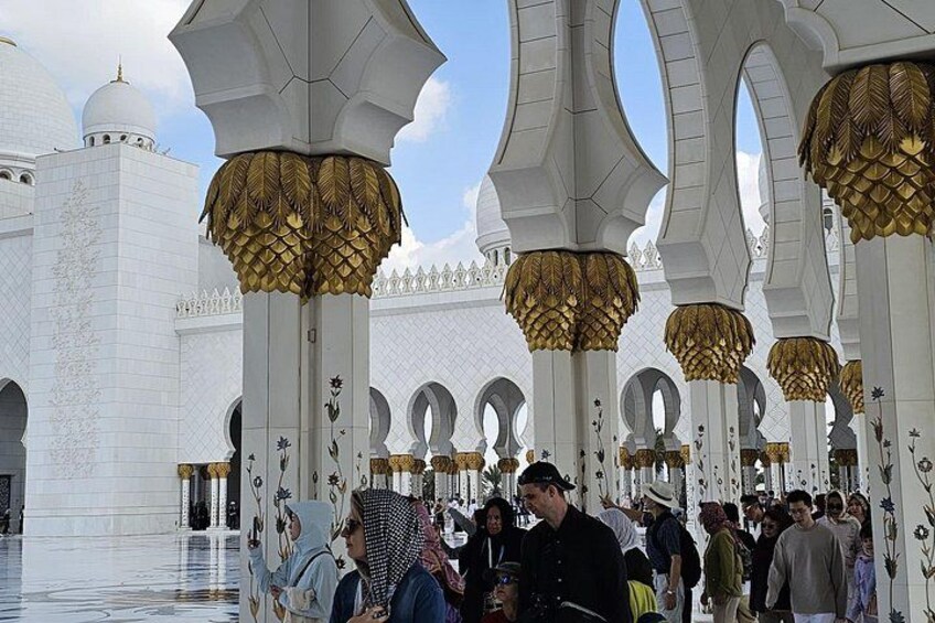 A large white building with golden arches and columns, surrounded by a crowd of people. 3
