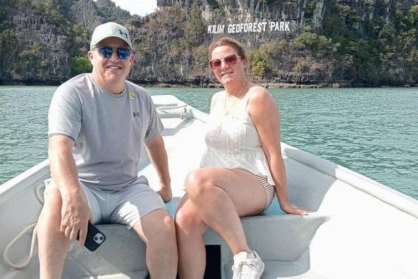 Two people on a boat in a body of water with a rocky landscape in the background. 5