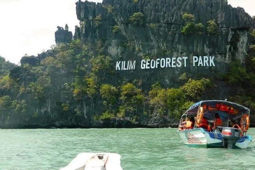 A boat on water with a rocky cliff and trees in the background labeled 'Kilim GeoForest Park.' 1