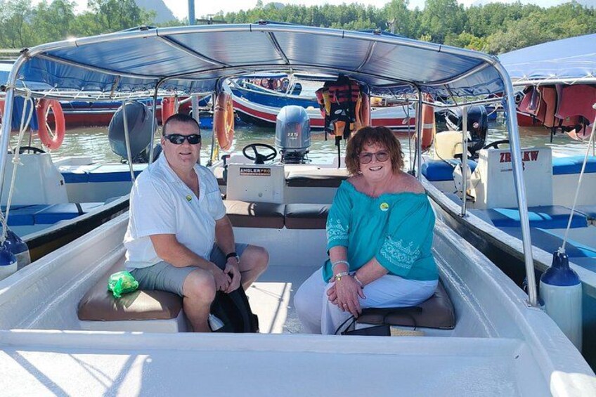 Two people on a boat with a canopy, surrounded by other boats. 4
