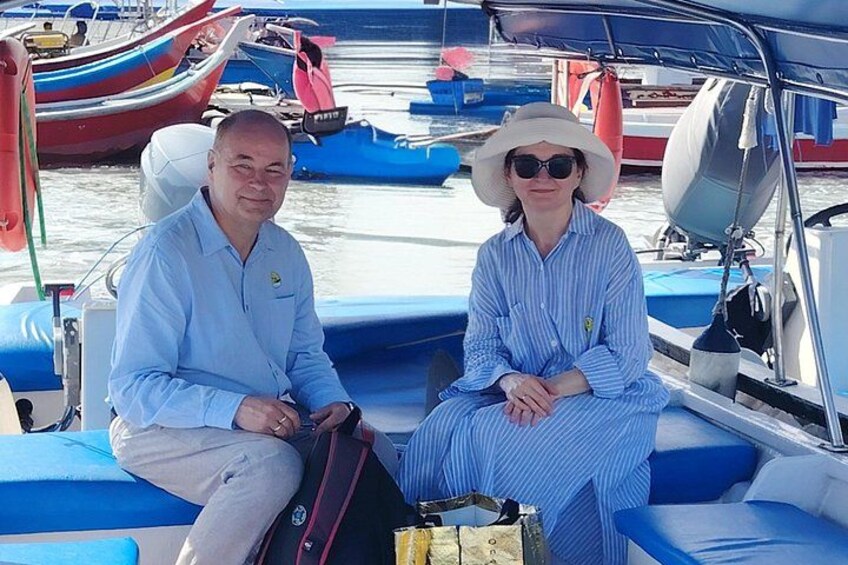 Two people on a boat with blue seats, surrounded by other boats. 2