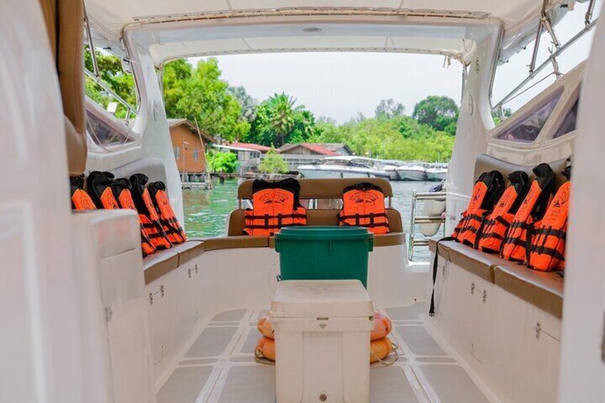 A boat interior with life jackets on the seats and a green cooler on the floor. 3