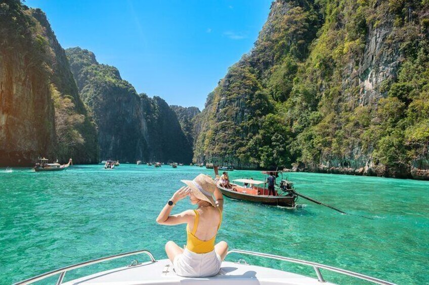 A woman on a boat in a turquoise sea surrounded by cliffs. 1