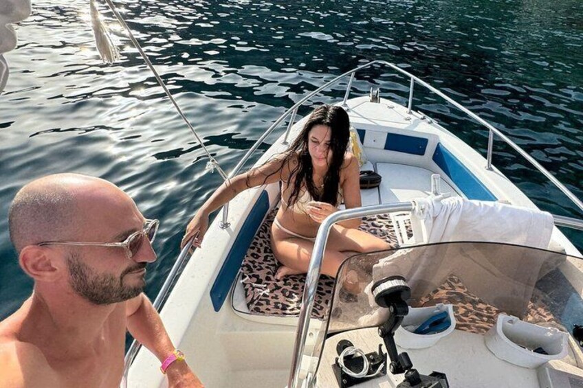A boat with two people, one seated and one standing, on calm water. 4