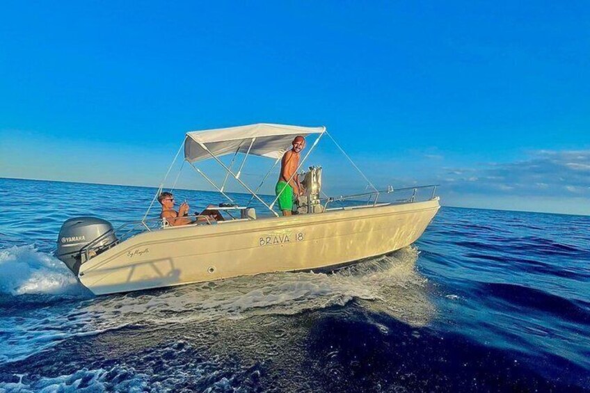 A small, cream-colored boat with 'BRAVA 18' on its side, moving through calm blue waters under a clear sky. 5