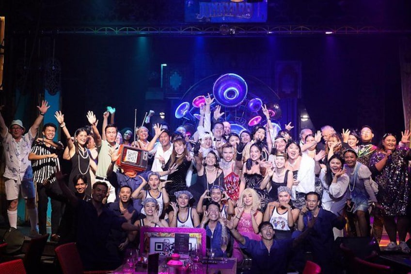 A group of people on a stage with a DJ booth and musical instruments. 2
