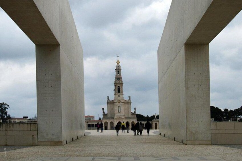 A large open plaza with a prominent church tower in the background, surrounded by concrete structures. 4