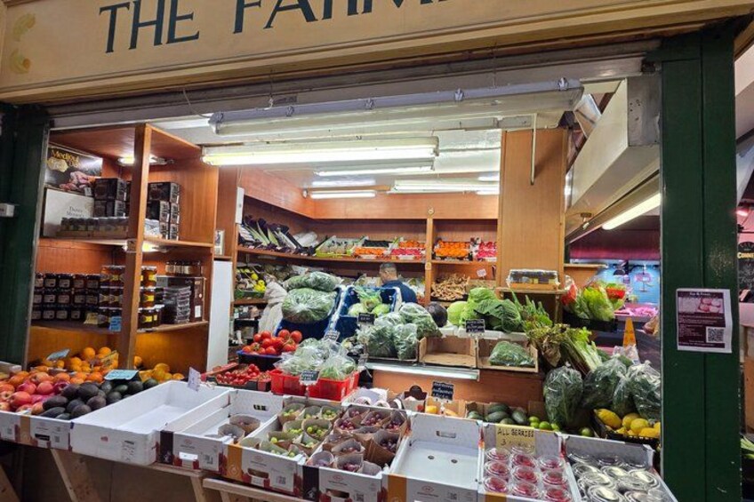 Interno di un negozio di alimentari con frutta e verdura fresca in mostra, scaffali in legno e una varietà di prodotti confezionati. 2