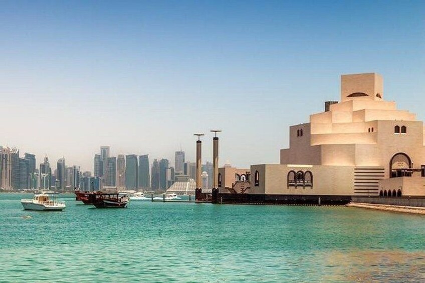 A waterfront with a modern building, boats, and a city skyline. 3