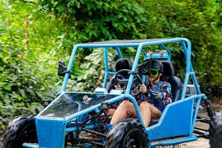 A person driving a blue off-road vehicle through a forested area. 5