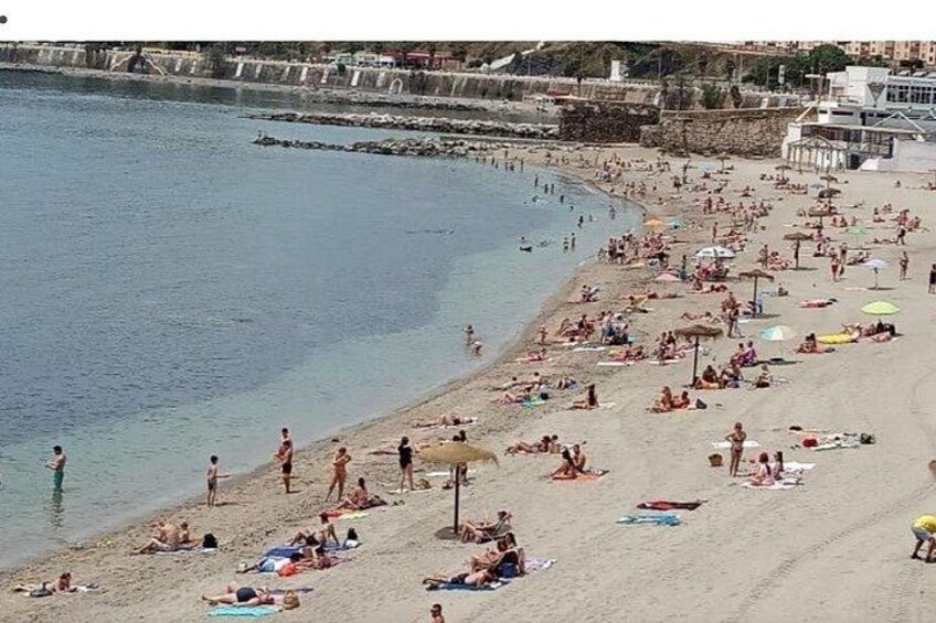 A crowded beach with people sunbathing and swimming. 5