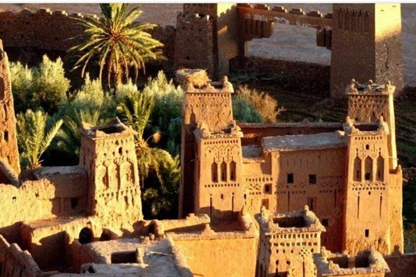 A historical site with ancient architecture, palm trees, and a clear sky. 1