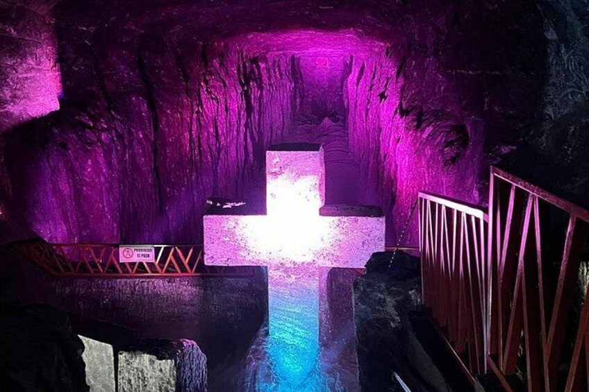 A cave with purple lighting, a cross, and a water feature. 3