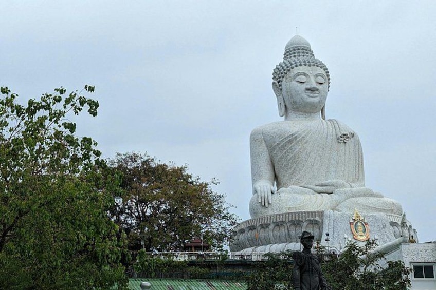 Un'imponente statua seduta di Buddha, circondata da alberi e da una statua più piccola. 4