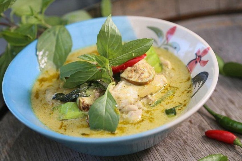Una ciotola di zuppa con foglie verdi e peperoncini rossi. 2