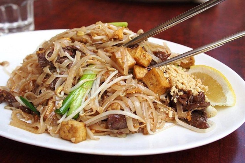 Un piatto di noodles Pad Thai con tofu, arachidi e spicchio di limone. 3