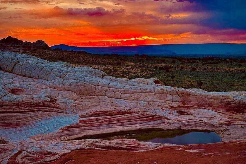 A sunset over a rocky landscape with a small pond. 4